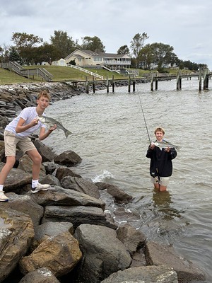 Two people on a shoreline each holding a fish